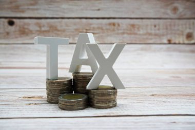 Tahta zemin üzerinde bozuk para yığını olan vergi alfabesi harfleri