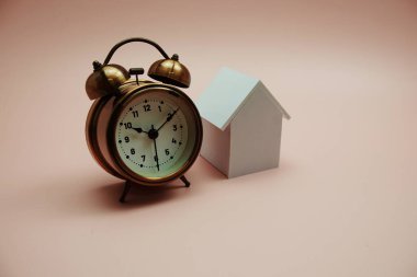 Pembe arka planda ev modeli ve alarm saati