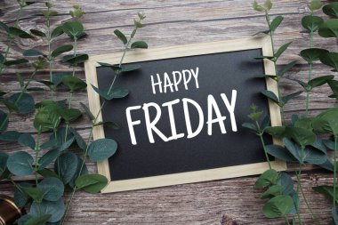 Ahşap zemin üzerinde yeşil okaliptüs süslemesi olan tahta tahtaya Mutlu Cuma tipografi metinleri