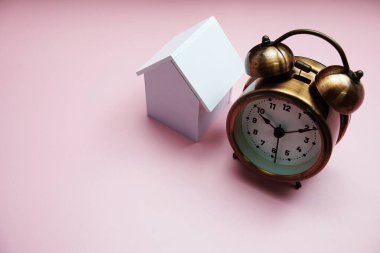 Pembe arka planda ev modeli ve alarm saati