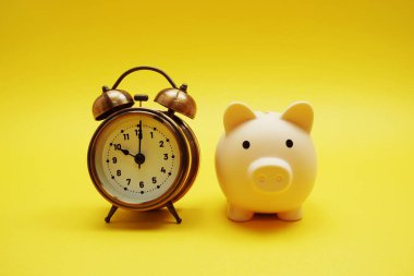 Kumbaralı ve alarmlı saat, sarı arkaplanda yer kopyası var.