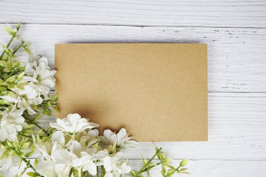 Tahta zemin üzerinde beyaz papatya çiçekli boş bir kağıt kart vardı.