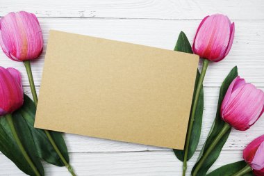 Tahta arka planda pembe lale çiçekli boş kağıt kart vardı.