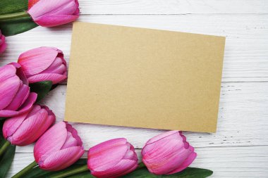 Tahta arka planda pembe lale çiçekli boş kağıt kart vardı.