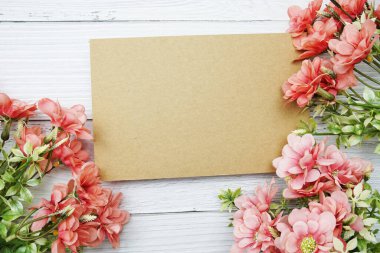 Tahta zemin üzerinde pembe papatya çiçeği bezi olan boş bir kağıt kart.