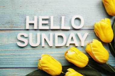 Merhaba, ahşap zemin üzerinde sarı lale çiçeği olan Pazar alfabesi.