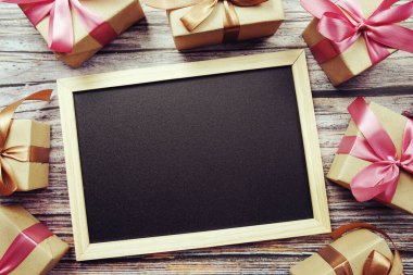 Ahşap arka planda pembe kurdeleli hediye kutuları