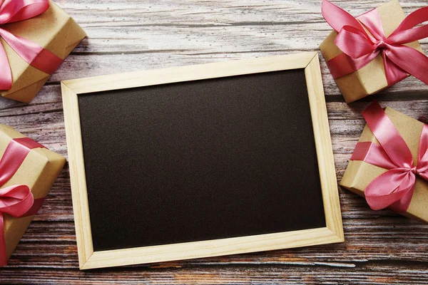 Ahşap arka planda pembe kurdeleli hediye kutuları