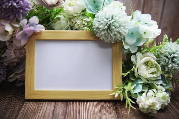 Ahşap zemin üzerinde çiçek buketi olan boş çerçeve dekorasyonu