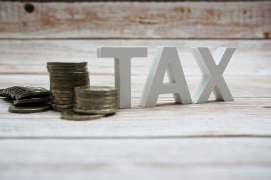 Tahta zemin üzerinde bozuk para yığını olan vergi alfabesi harfleri