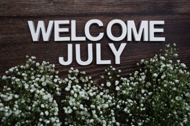 Hoş geldiniz Temmuz alfabesi harfleri ahşap arka planda çiçekler