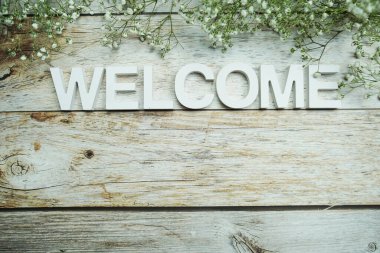 Tahta zemin üzerinde çiçekler olan alfabe harflerini hoş geldiniz.