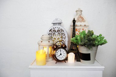 Ev dekorasyonu aksesuarları Eyfel heykeli, çalar saat, fener ve LED mum ışığı beyaz ahşap masa üzerinde.