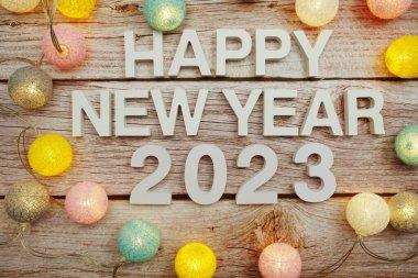 Yeni yılınız kutlu olsun 2023 alfabesi. Ahşap zemin üzerinde LED pamuk topları ile süsleyin.