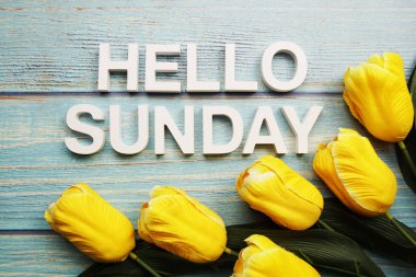 Merhaba, ahşap zemin üzerinde sarı lale çiçeği olan Pazar alfabesi.