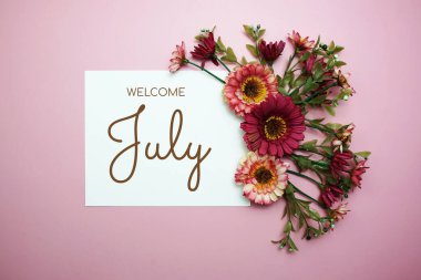 Welcome July typography text with flowers on pink background