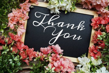 Tahta tahtaya yazılmış tipografi metni için teşekkür ederim. Ahşap arka planda çiçek buketi süslemesi.