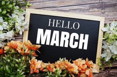 Hello March typography text written on wooden blackboard with flower bouquet decorate on wooden background