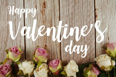 Ahşap arka planda gül çiçekleri buketli Sevgililer Günü tipografisi metnin kutlu olsun.