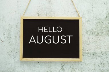 Hello August typography text on blackboard hanging against on the concrete background