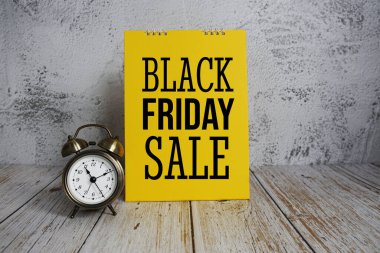 Black Friday Sale text message and alarm clock on wooden background