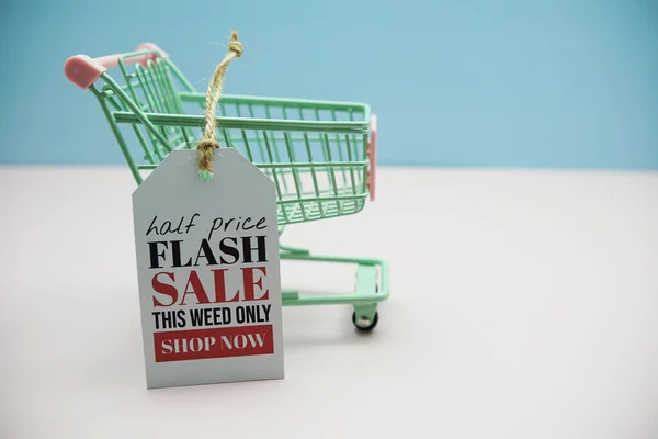 Flash Sale text message on price tax with shoppint trolley cart on blue and pink background