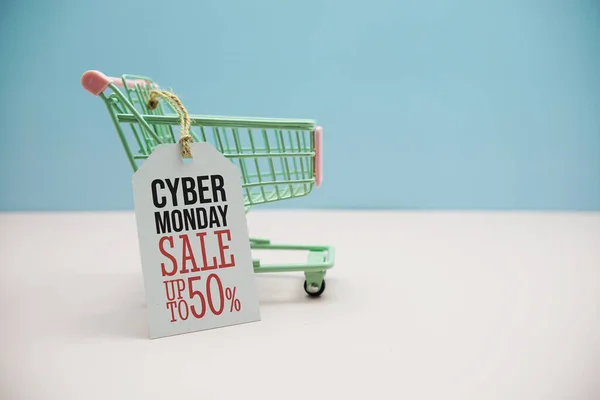 Cyber Monday Sale 50%  text message on price tax with shoppint trolley cart on blue andp pink background