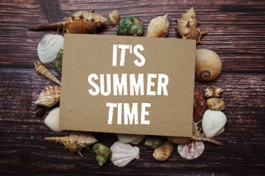 It's Summer Time text message decoration with seashell on wooden background