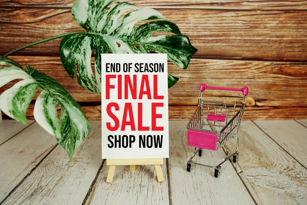 End of Season Sale text message decoration with shopping cart on wooden background
