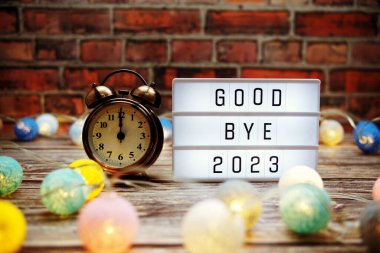 Goodbye 2023 text in light box with alarm clock and LED cotton balls decoration
