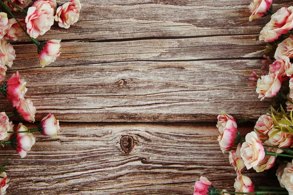 Pink roses flowers border frame on wooden background