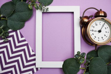 White Frame with clock and Eucalyptus leaves on purple background