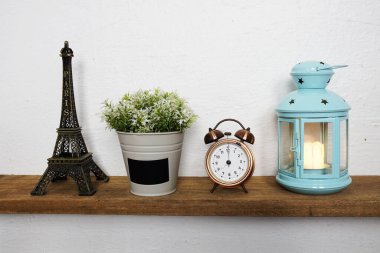 Eiffel tower statue, artificial plant, vintage alarm clock and blue lantern with LED candle light on wooden shelves