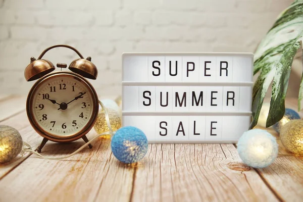 Super Summer Sale text in light box with LED cotton balls decorated on wooden background