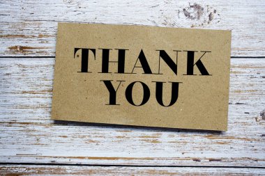 Thank You written on paper card top view of wooden background