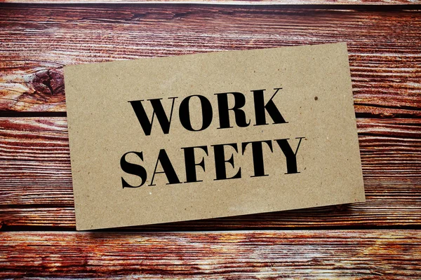 Work Safety written on paper card top view of wooden background