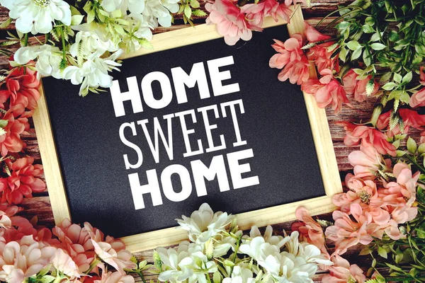 Home Sweet Home typography text written on wooden blackboard with flower bouquet decorate on wooden background