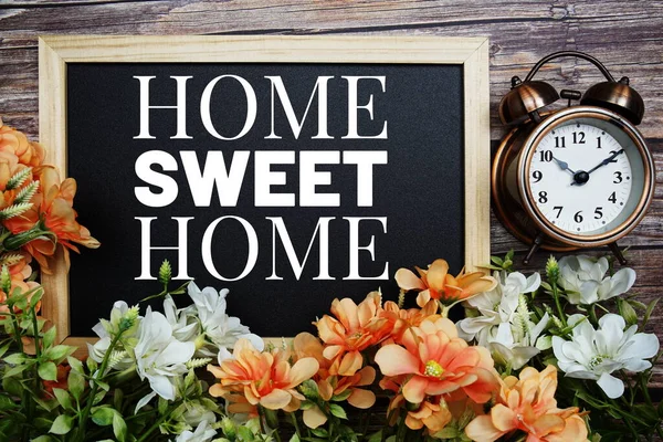 Home Sweet Home typography text written on wooden blackboard with flower bouquet decorate on wooden background