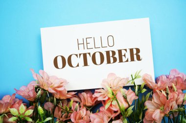 Hello October text message with flower decoration on blue background