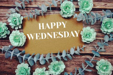 Happy Wednesday typography text on paper card decorate with flower on wooden background