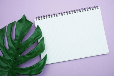 Monstera yapraklarının mor arkaplanda olduğu kopya için boş defter sayfasının kopyası