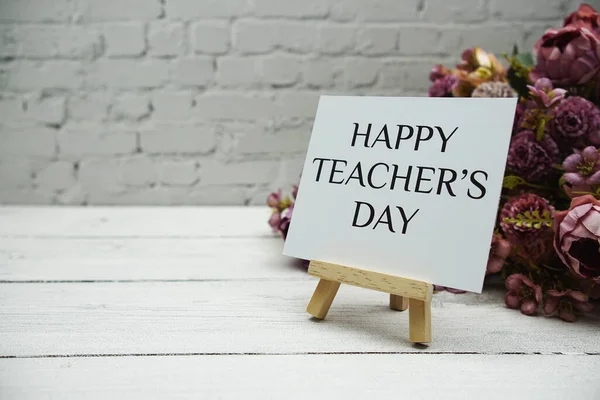 Happy Teachers Day text on white brick wall and wooden background