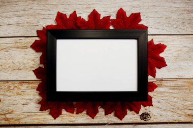 Ahşap zemin üzerinde akçaağaç yaprakları olan fotoğraf çerçevesini boşalt