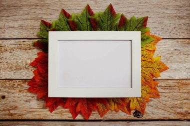 Ahşap zemin üzerinde akçaağaç yaprakları olan fotoğraf çerçevesini boşalt