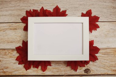 Ahşap zemin üzerinde akçaağaç yaprakları olan fotoğraf çerçevesini boşalt
