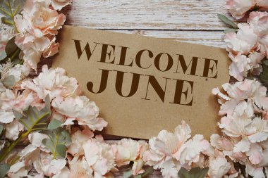 Ahşap arkaplanda çiçek çerçeveli Haziran tipografi metnine hoş geldiniz