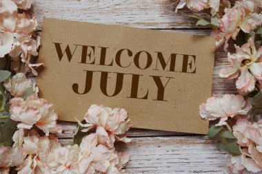 Tahta arkaplanda çiçek çerçeveli Temmuz tipografi metnine hoş geldiniz