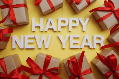 Sarı arka planda hediye kutuları olan mutlu yeni yıl alfabesi mektupları