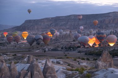 Sıcak hava balonları uçuyor ve Türkiye 'nin Kapadokya kentinde mavi gökyüzü arka planında. Peri bacalarının üzerinde sıcak hava balonuyla uçmak Kapadokya 'daki en güzel turistik etkinliklerden biridir..
