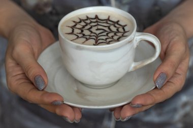 A cup of decorated latte in female hands